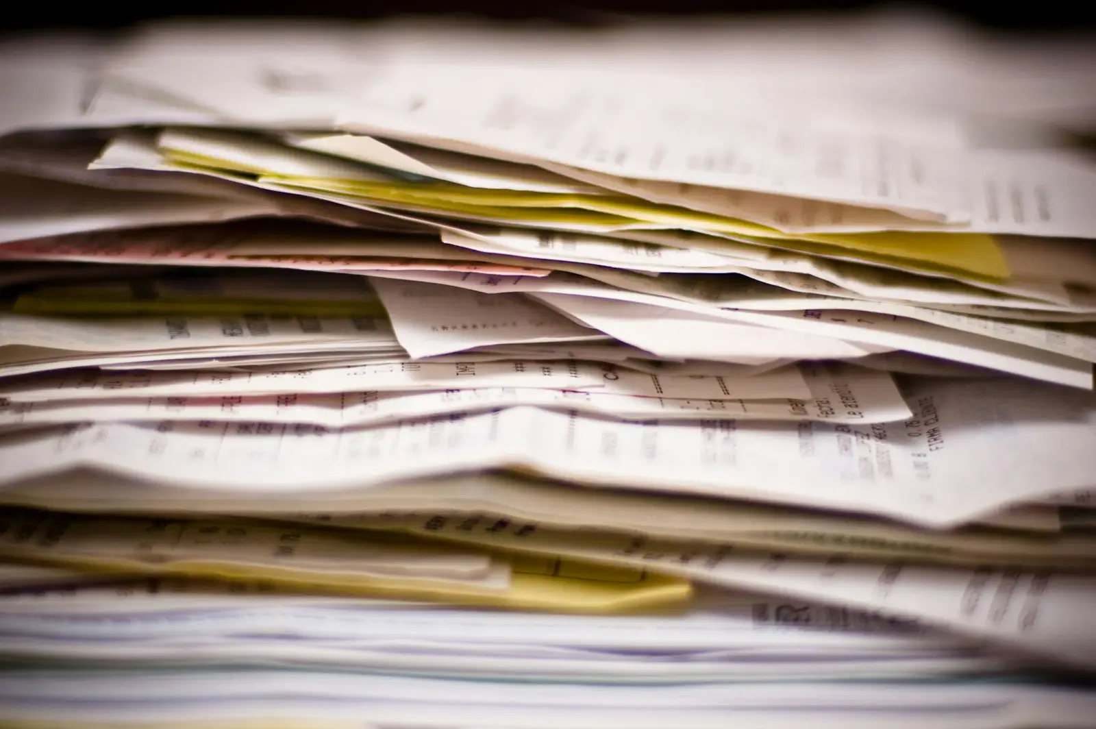 A thick stack of paper documents and invoices