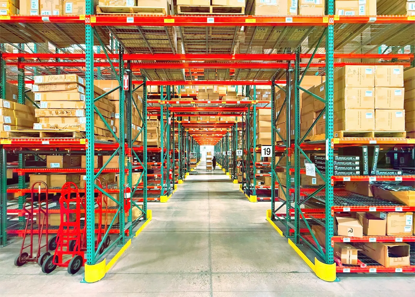 A long warehouse aisle between tall shelves of boxes